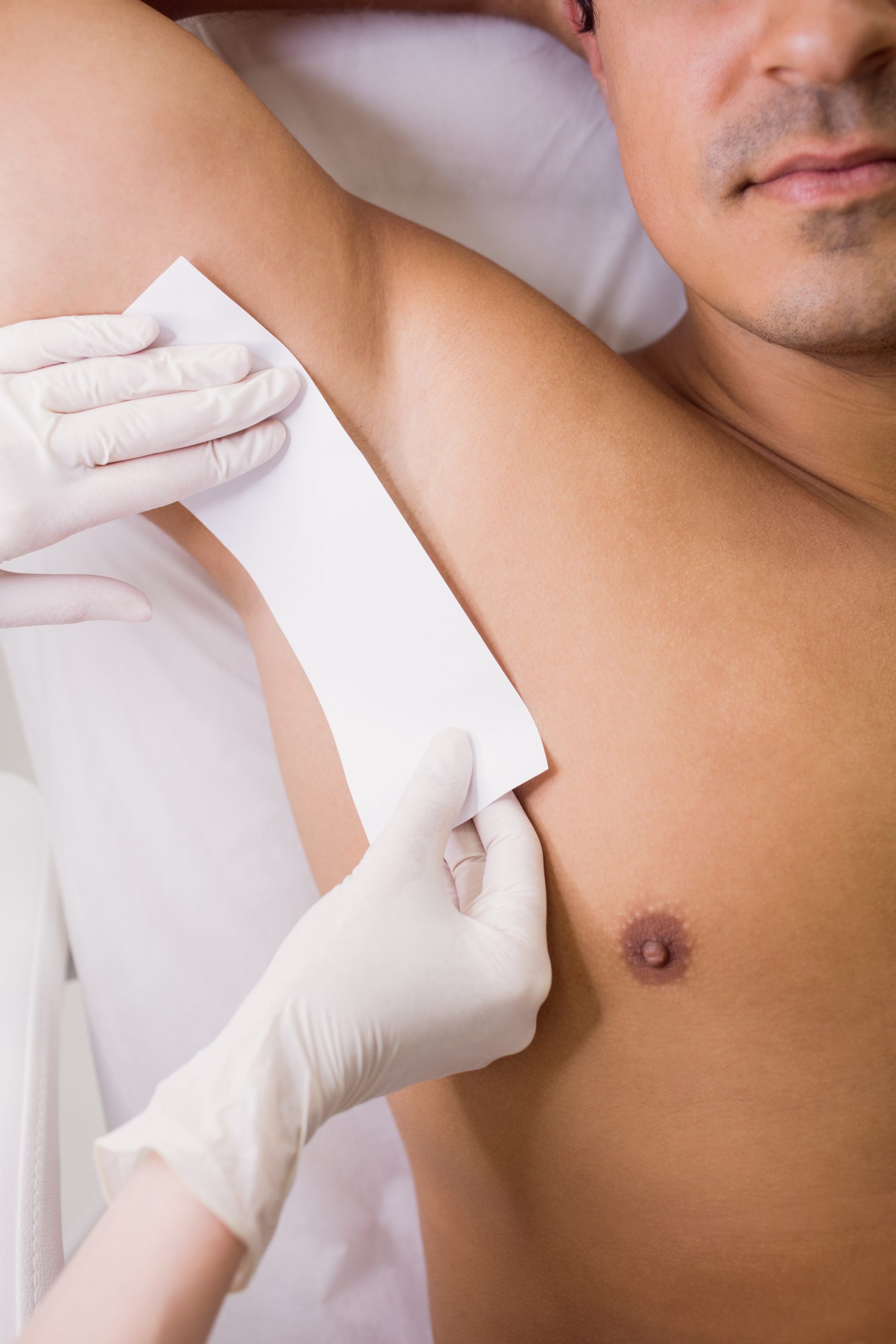 Close up of doctor waxing male patient skin in clinic